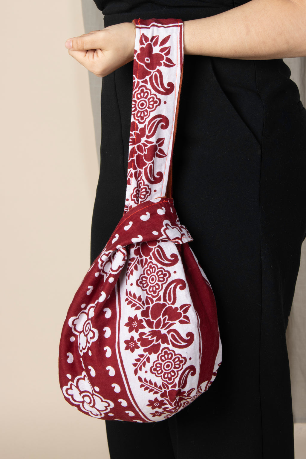 Sac Rihla fait main en gaze de coton orange et tissu comorien rouge, modèle réversible style knot bag porté à la main.